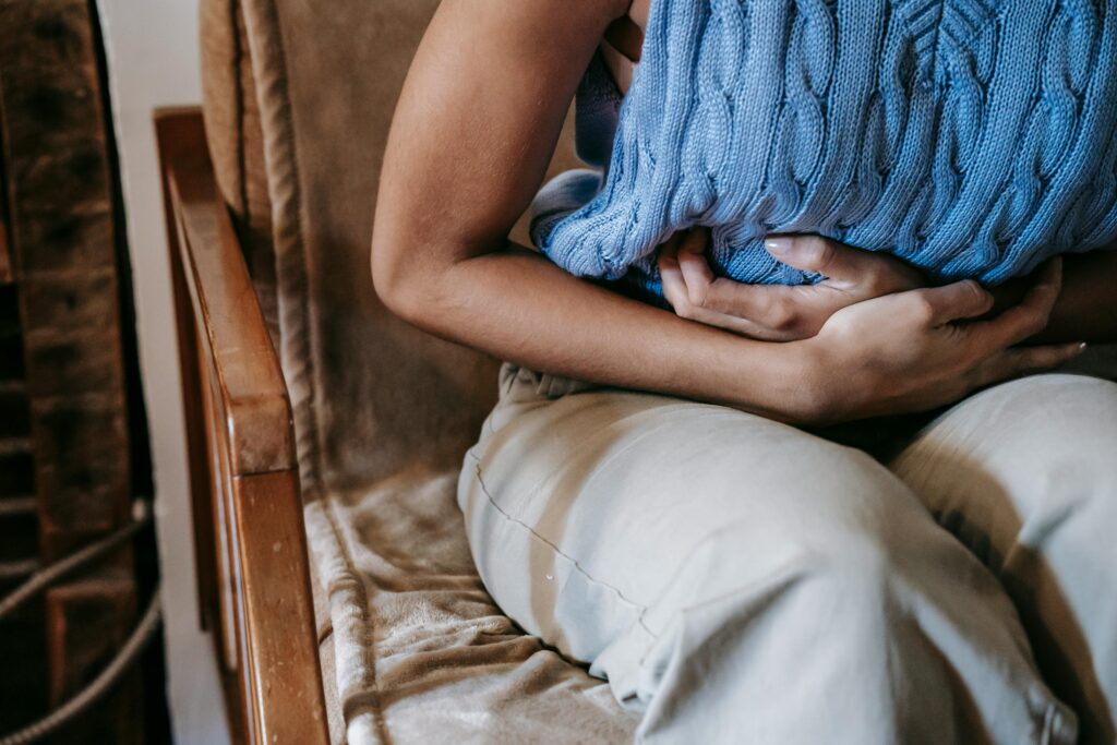 pexels-photo-5938358-5938358 Crop unrecognizable female touching belly while having acute pain in stomach sitting on couch